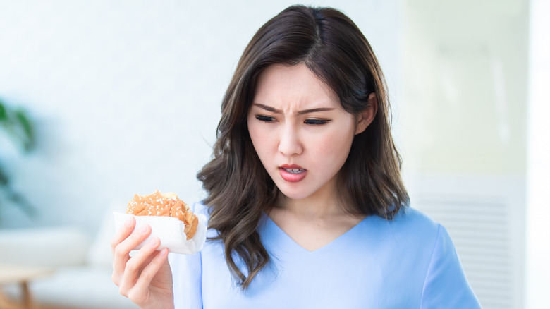 Woman looking questionably at half-eaten burger
