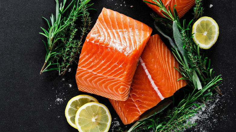 raw salmon surrounded by lemon and rosemary