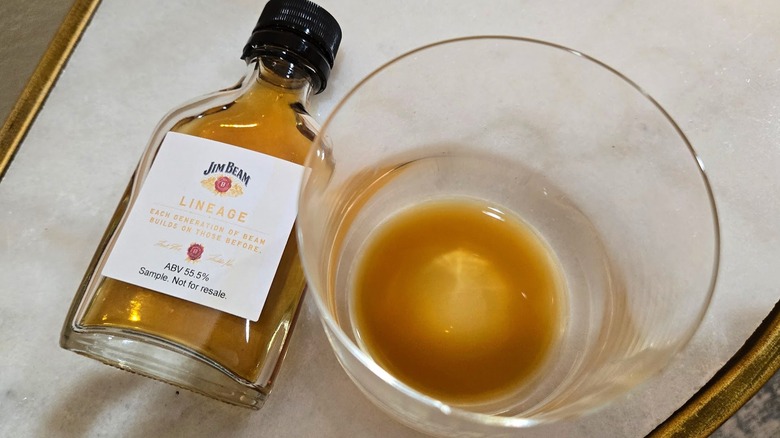 Glass of cloudy Jim Beam Lineage Batch #2 and sample bottle