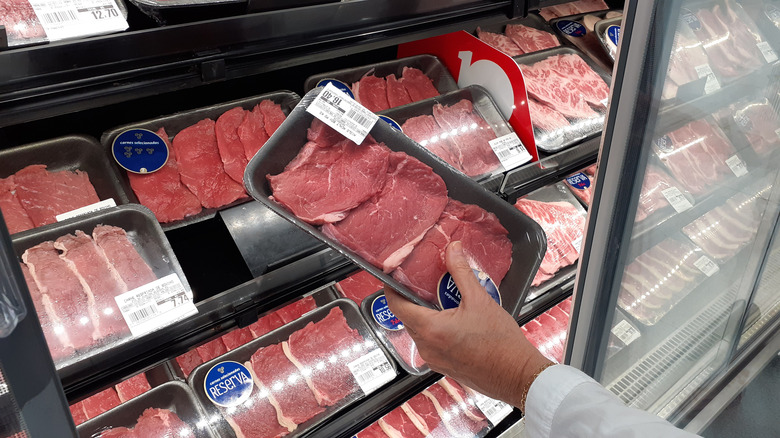 person picks up meat at store