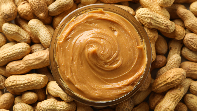 peanut butter in a bowl surrounded by peanuts