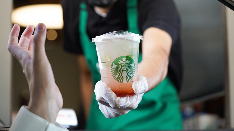 Barista handing out a Starbucks drive-thru order