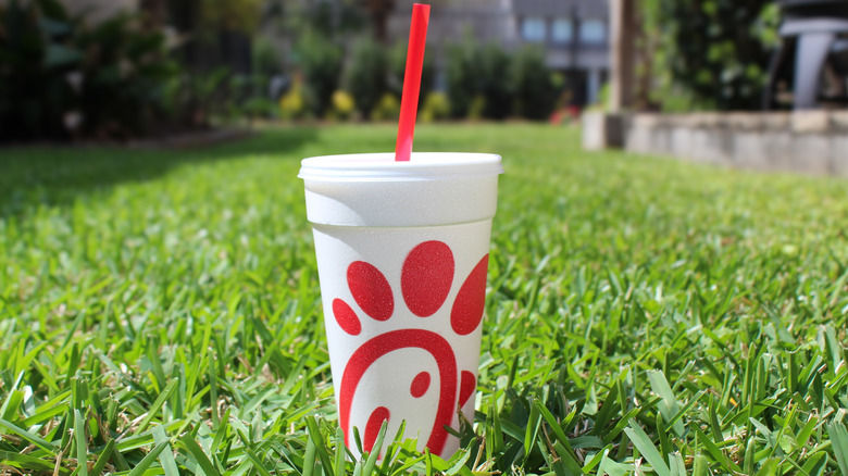 A Chick-Fil-A to-go drink in grass outside