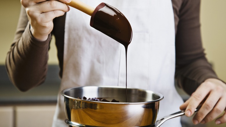 Melted chocolate dripping off spatula into pot