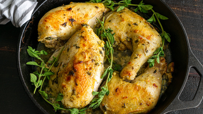 Baked chicken in a cast iron pan with herbs