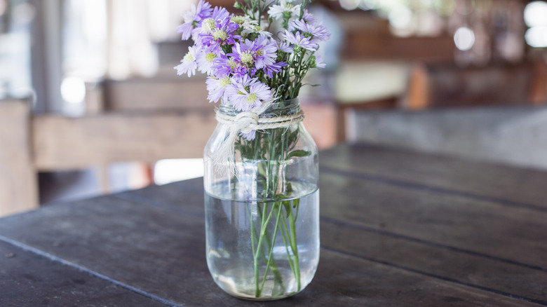 Flowers in a glass jar vase on brown table