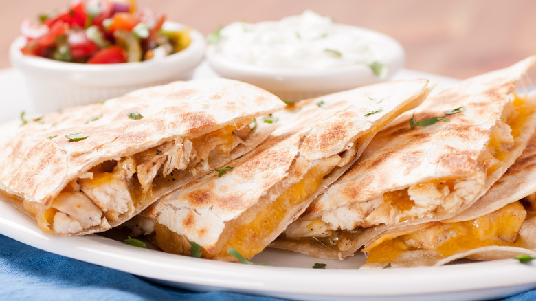 chicken and cheese quesadillas on while plate with sour cream and salsa