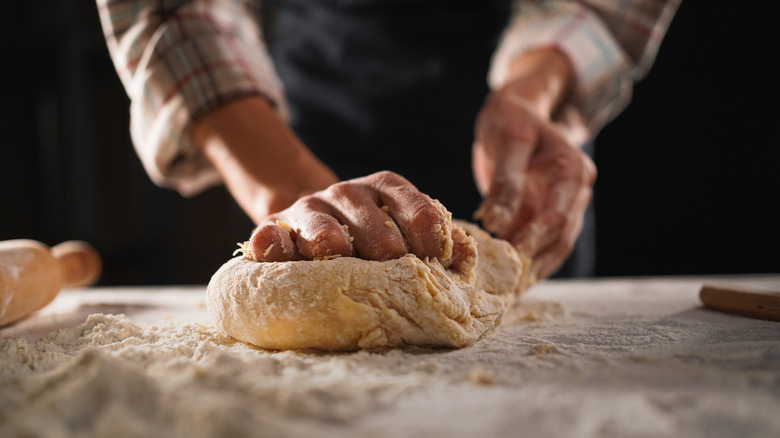 person kneading bread dough