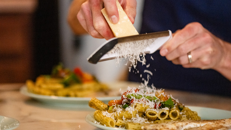 Person grating cheese on pasta