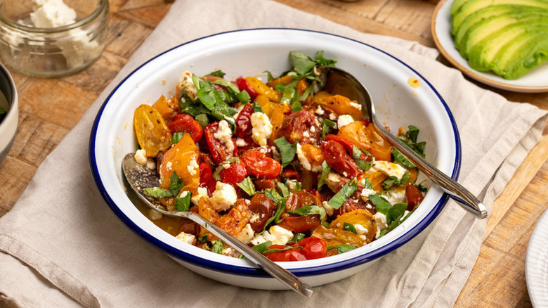 Roasted tomato, feta, and basil salad in a white bowl
