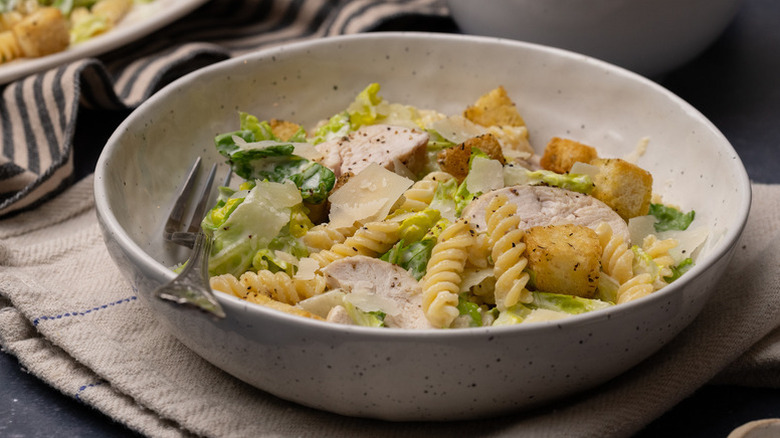 Bowl of Caesar chicken pasta salad with croutons and shaved Parmesan