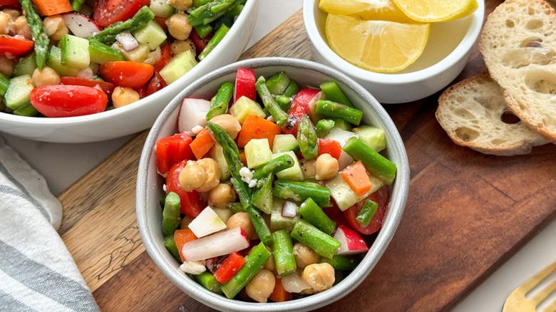 Bowls of chopped salad with chickpeas, asparagus, and radish