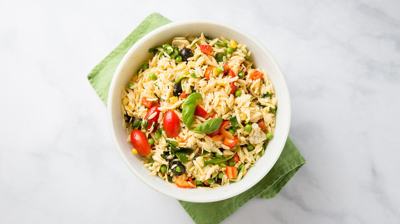 Bowl of orzo salad with tomatoes, peas, and basil
