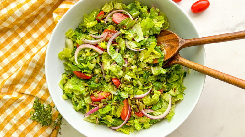 Bowl of green salad with tomatoes and red onions