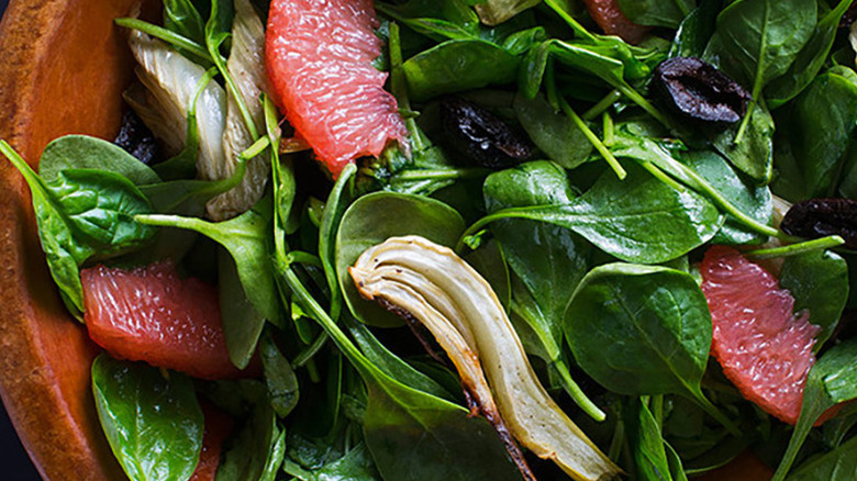 Close-up of spinach, fennel, and grapefruit salad in a wooden bowl