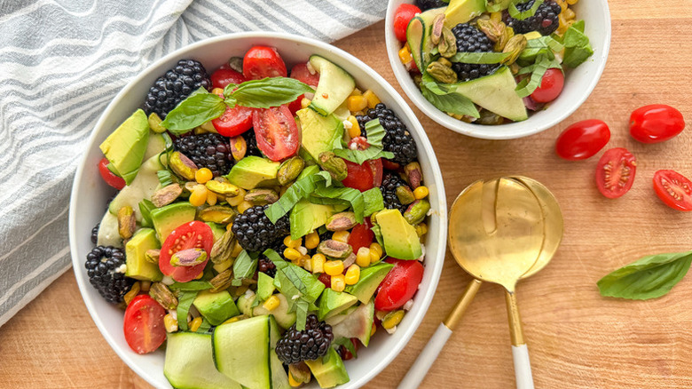 Bowls of salad with avocado, blackberries, and tomatoes