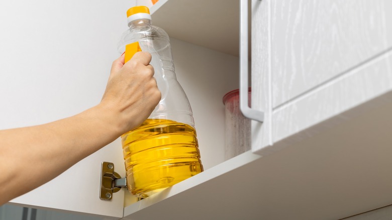 removing bottle of cooking oil from cupboard