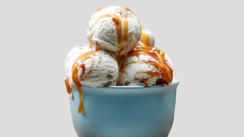 Blue bowl of ice cream scoops topped with caramel sauce