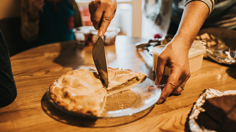 hand cutting an apple pie