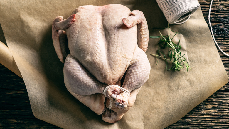whole raw chicken on baking paper with twine