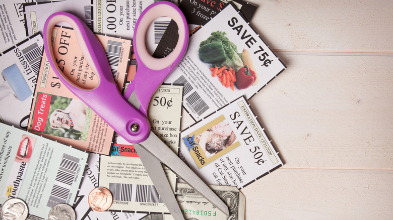 Scissors and coins on top of grocery coupons