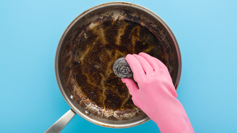 Foodie scrubbing a dirty pan with steel wool