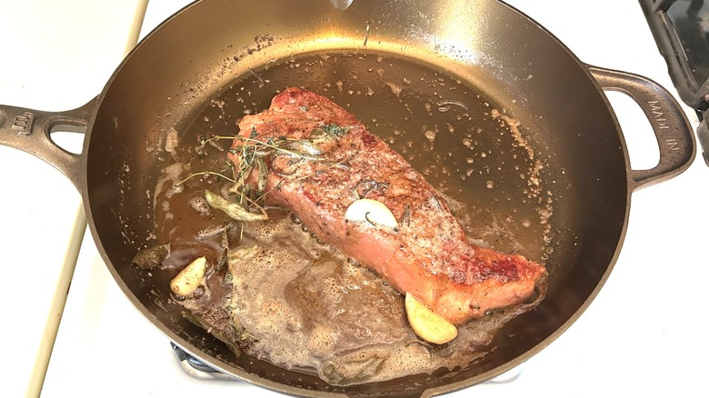 Butter basted strip steak in a Made In Seasoned Cast Iron 12" skillet with fresh herbs and garlic