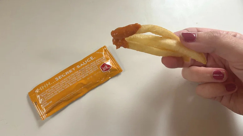 Hand holding fries with Jack In The Box secret sauce