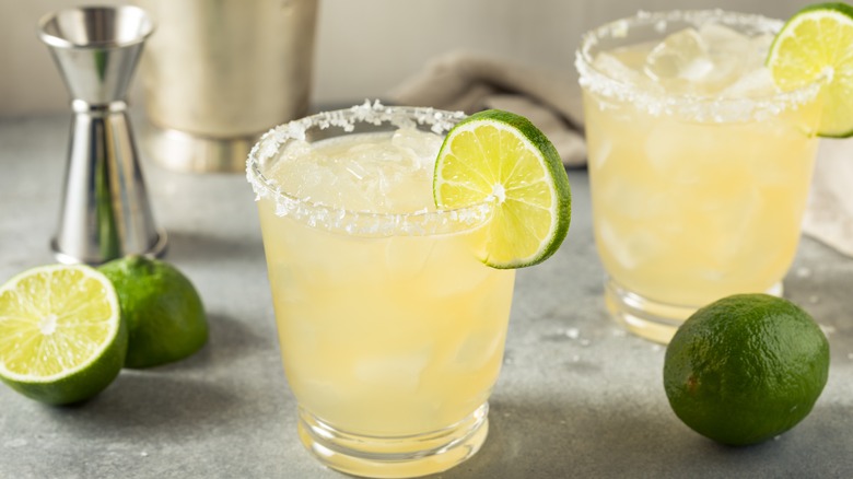 Two classic margaritas next to limes