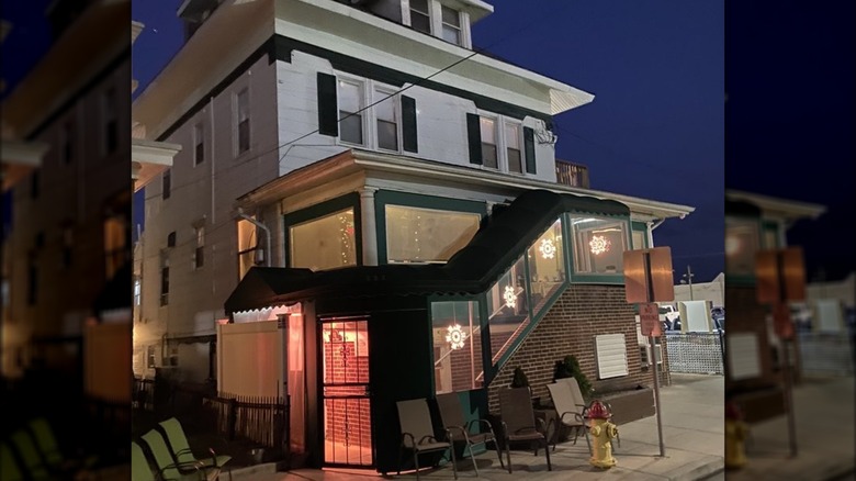 Exterior of white house with green awning covering stairs