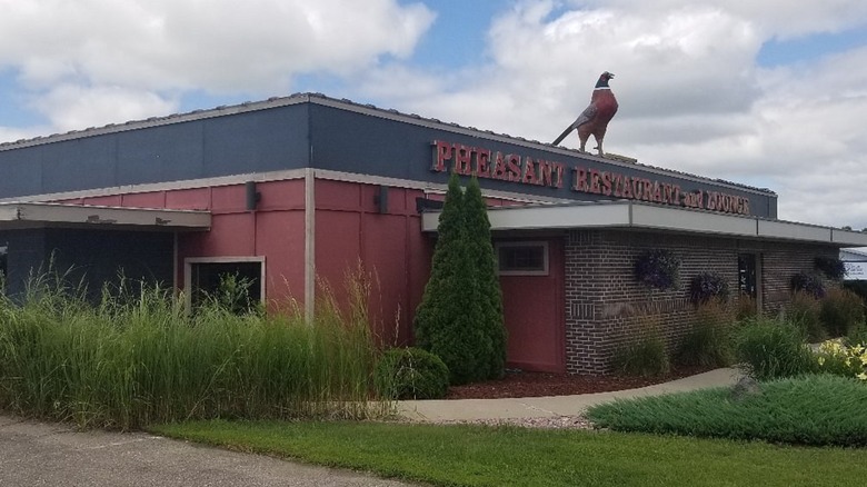 Exterior of black and red building with pheasant statue on top