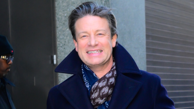 Jamie Oliver smiling in blue jacket with printed scarf