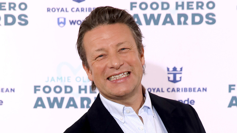 Jamie oliver smiling in front of white backdrop