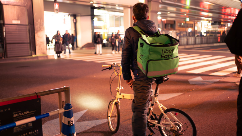 A Uber Eats bicycle rider on a street in Japan at night