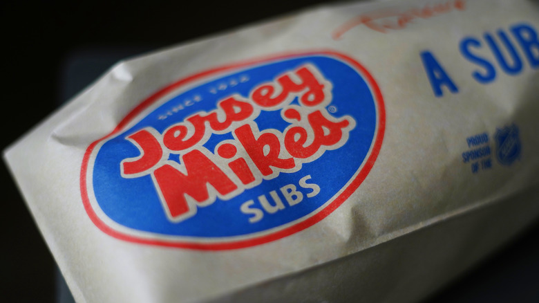 A Jersey Mike's sub wrapped in brown, logo-filled paper