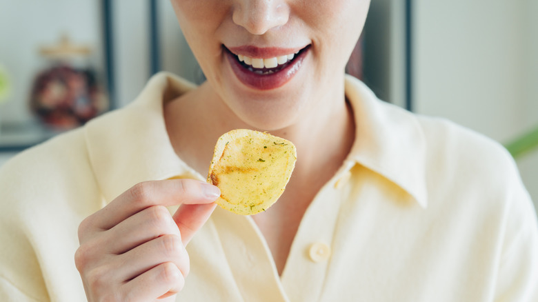 close up of woman's hand holding potato chip