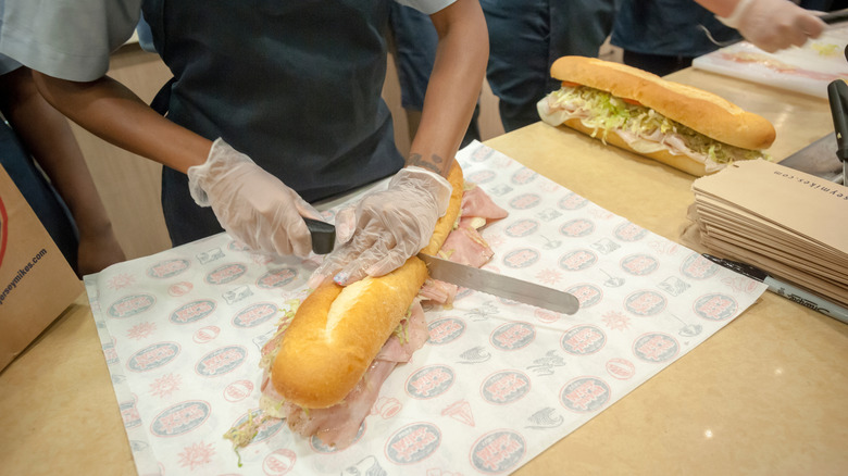 Jersey Mike's employee cutting a sub in half