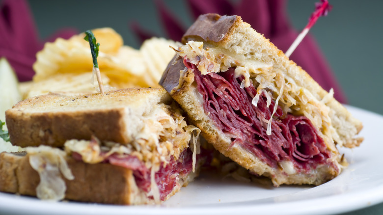 A toasted Reuben sandwich sliced in half showing Pastrami and sauerkraut inside