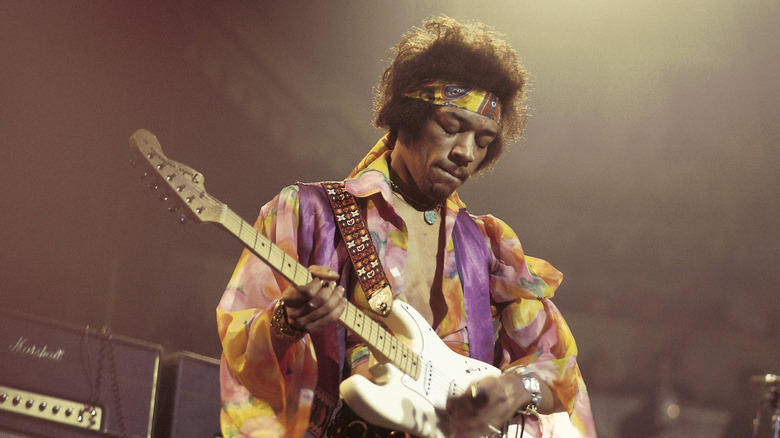 Jimi Hendrix strums an electric guitar on stage with his eyes closed