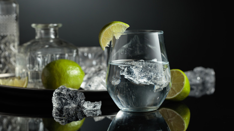 Glass of clear alcohol with ice and a lime
