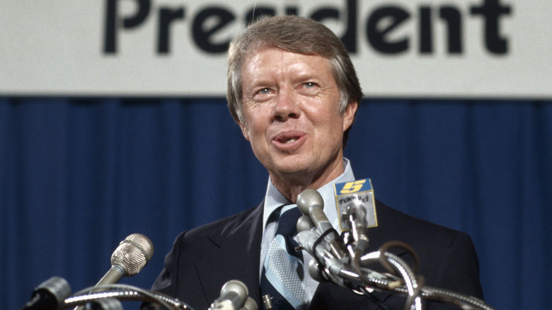 Jimmy Carter giving a speech into a bank of microphones