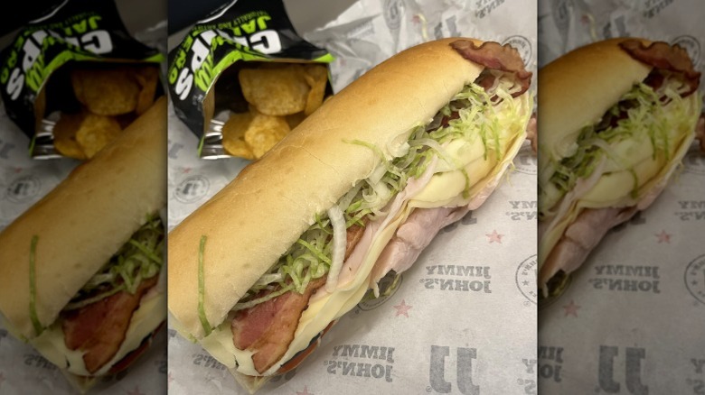 Jimmy John's Beach Club with bacon added next to opened bag of chips