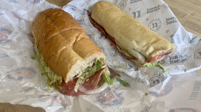 Jimmy John's and Jersey Mike's italian subs on top of wrappers with wood background