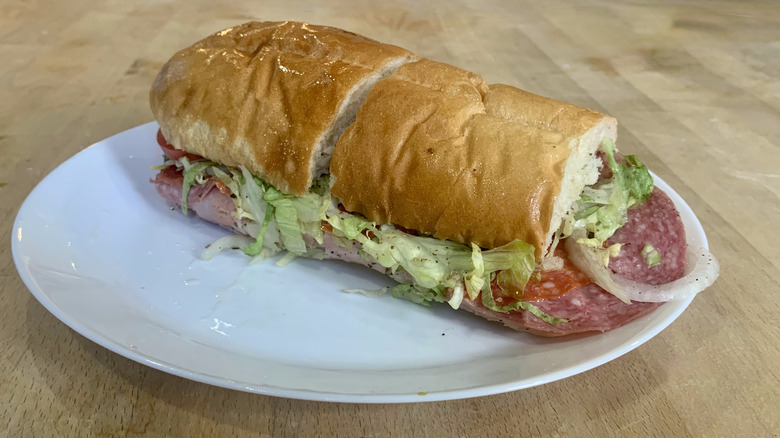 Jersey Mike's italian sub unwrapped on white plate with wood background
