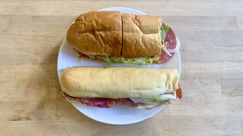Jimmy John's and Jersey Mike's italian subs unwrapped on white plate with wood background