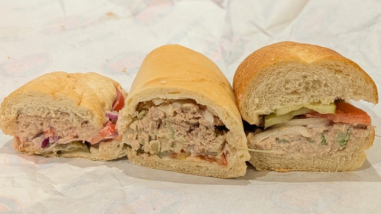 A cross-section of three-tuna subs, lined up on a piece of white paper
