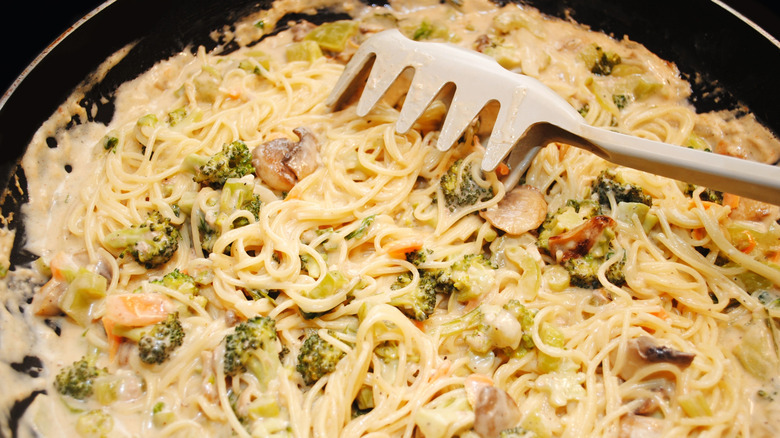 Closeup of creamy spaghetti with veggies in a pan