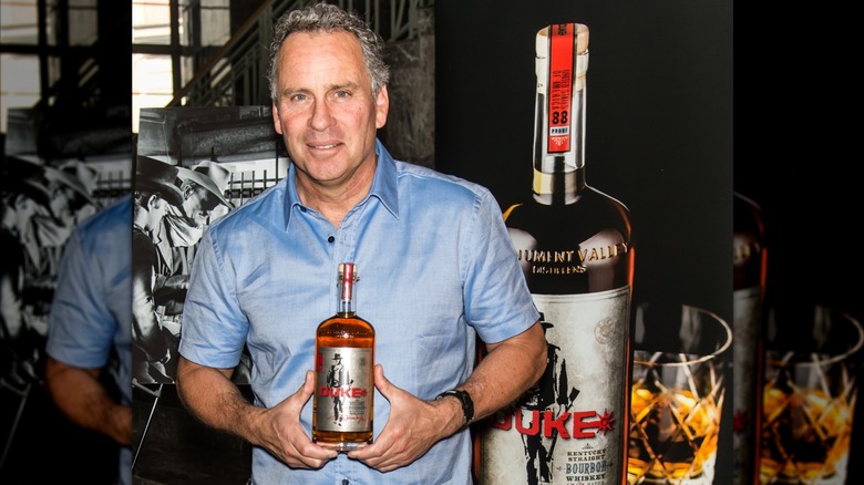 Ethan Wayne holding a bottle of Duke Bourbon.