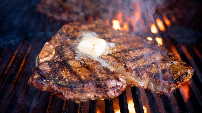 T-bone being grilled on flame with melted butter