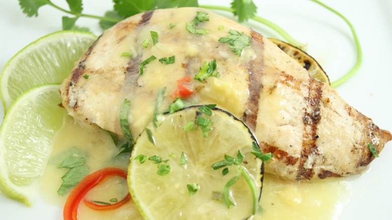 Tequila lime chicken with grill marks and topped with sauce, garnished with lime and chopped cilantro.